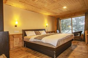a bedroom with a bed and a large window at Agyaat Vaas in Bāgi