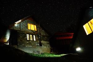 a house lit up at night with glowing windows at Agyaat Vaas in Bāgi