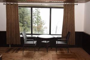 a table and chairs in a room with windows at Agyaat Vaas in Bāgi