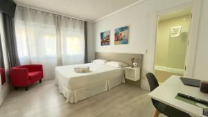 a bedroom with a white bed and a red chair at Hotel Gabriel y Galán in Salamanca