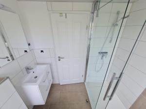 a white bathroom with a shower and a sink at Ferienwohnung Inselblick Vitzdorf in Fehmarn