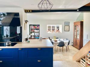 a kitchen with blue cabinets and a dining room at Cadre d'exception et nature - 2 Maisons - 15 pers max in Aigné