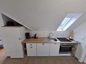 a kitchen with white cabinets and a sink and a window at Ferienwohnung Küstennest Vitzdorf in Fehmarn