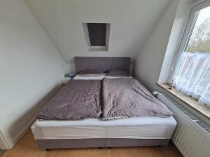 a bed in a small room next to a window at Ferienwohnung Küstennest Vitzdorf in Fehmarn