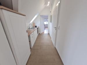 a kitchen with white cabinets and a long hallway at Ferienwohnung Küstennest Vitzdorf in Fehmarn