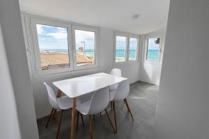 a white dining room with windows and a white table and chairs at Fiorucci Apartments - Marco's House in Focene