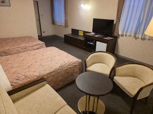 a hotel room with a bed and a table and chairs at Nobeoka Urban Hotel in Nobeoka
