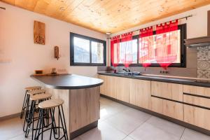 a kitchen with a bar with stools and a sink at Chalet Les Lys - Tout Confort in Valloire +5 photos