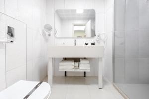 a white bathroom with a sink and a mirror at Avwan Hotels Collection in İzmir