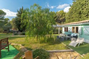 a garden with a blue house and a tree at Le Colibri in La Ciotat