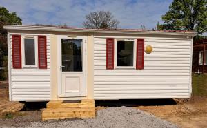a small white house with red shuttered windows at Les cabanes de Condé in Condé-sur-Vesgre