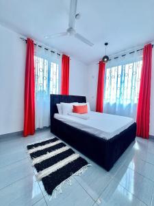 a bedroom with a bed with red curtains and a rug at Auryhomes in Mombasa