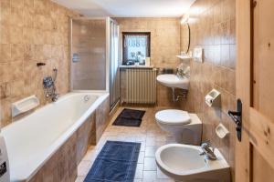 a bathroom with two sinks and a tub and a toilet at Innerforchhof Schnals in Madonna +28 photos