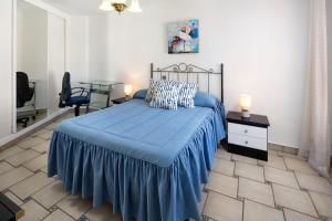 a bedroom with a bed with a blue blanket and a table at Bloque 76 in Torrox +17 photos