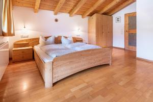 a large wooden bed in a room with wooden floors at Mansardenwohnung Egart in Resia