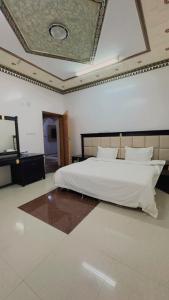 a bedroom with a large white bed and a mirror at شقق مخدومه in Najran