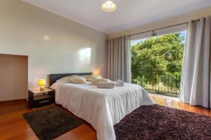 a bedroom with a white bed and a large window at Refugio Dourado in Água de Pena