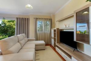 a living room with a couch and a flat screen tv at Refugio Dourado in Água de Pena