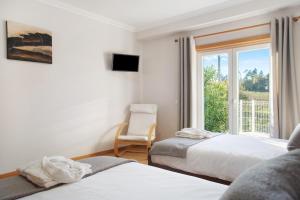 a bedroom with two beds and a window with a chair at Villa Rosa com Piscina e Jacuzzi in Salir de Matos +24 photos