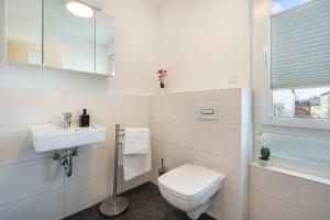 a white bathroom with a toilet and a sink at Apartment-Ernst in Finsterwalde +21 photos