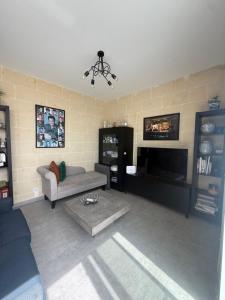 a living room with a couch and a tv at Azure Dome Residences in Għajnsielem
