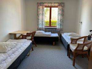 a room with two beds and a table and a window at Pension Elmehøj in Hjertebjerg