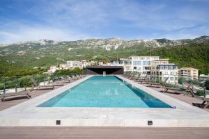 a swimming pool with chairs and mountains in the background at Sobre Suites in Bečići