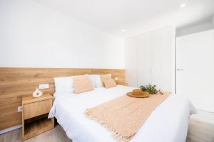 a bedroom with a large white bed with a wooden headboard at White suites 3 in Cala d´Or +20 photos