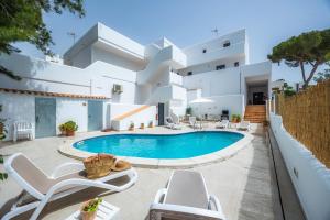 a villa with a swimming pool in front of a building at White suites 3 in Cala d´Or
