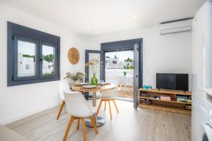 a living room with a table and chairs and a tv at White suites 3 in Cala d´Or