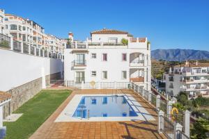 a large white building with a swimming pool in a yard at Astonishing view modern apartment in Sitio de Calahonda