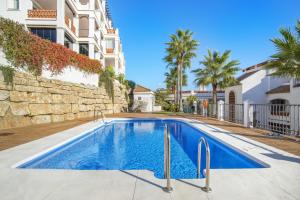 a swimming pool in front of a building at Astonishing view modern apartment in Sitio de Calahonda