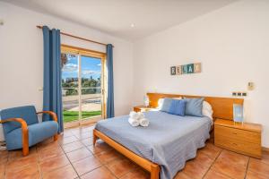 a bedroom with a bed and a chair and a window at Villa Alvor in Alvor +30 photos