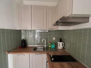 a kitchen with white cabinets and a sink and green tiles at "Ivanera" Postira otok Brač in Postira
