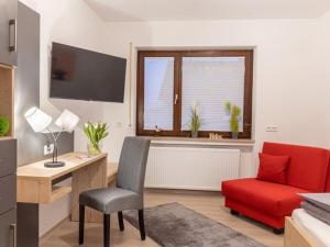 a living room with a desk and a red chair at Comfort Apartment Buchhorn in Friedrichshafen