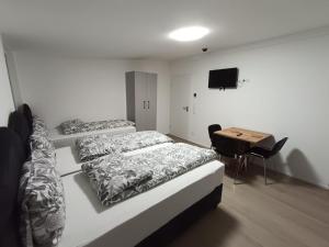 a bedroom with three beds and a desk and a television at City Apartments Göppingen in Göppingen