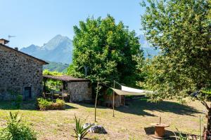 a house with a tent in a yard with mountains at Casale di Polly in Garfagnana in Minucciano