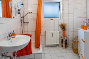 a bathroom with an orange shower curtain and a sink at Hotz in Radolfzell am Bodensee +17 photos