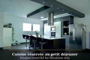a kitchen with a refrigerator and stools in it at B&B Chambre cosy avec petit-déjeuner inclus Parking prive & box vélo sur la Route des vins in Issenheim