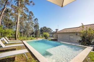 a swimming pool with two chairs and a house at Villa da Floresta in Arcos