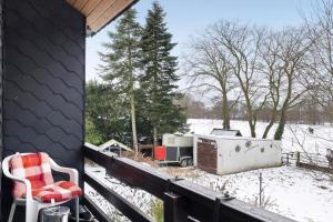 a snowy porch with a chair and a stove at Mole Valley Ranch Fewo2 in Elmlohe