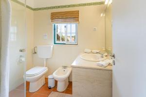 a white bathroom with a toilet and a sink at Casa de praia na costa da Galé in Melides +21 photos