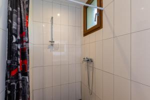 a white tiled bathroom with a shower and a window at Les Sources Gîte calabert in Chambonas +17 photos