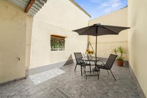 a patio with a table and chairs and an umbrella at Casa Vacanze Sa Domixedda in Guspini