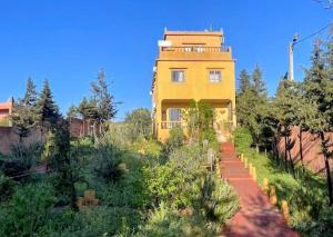 a yellow building on a hill next to a dirt road at Le petit Jardin in Demnat