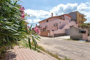 a street with a house and a plant with pink flowers at Casa Loretta 3 in Valledoria