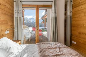a bedroom with a bed and a balcony with a view at Chalet Arvina in Saint-Jean-dʼArves