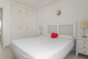 a white bedroom with a white bed with a red heart pillow at Casa Ricardo in Barbate