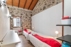 a bedroom with two beds in a room with stone walls at Casa Eloisa in Teror