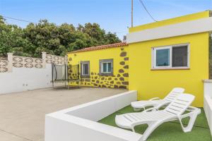 a yellow house with two white chairs on a patio at Casa Eloisa in Teror